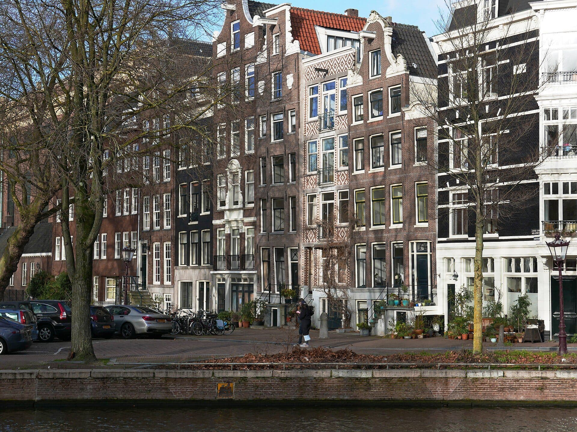 A row of old canal house facades in Amsterdam reflected in the water of the Nieuwe Herengracht